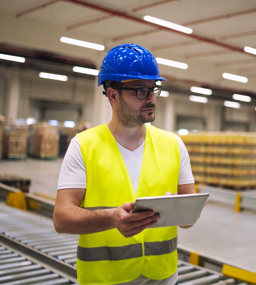 Uomo in un magazzino di logistica che lavora con in mano un tablet